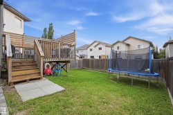 Spacious backyard featuring a wooden deck with slatted privacy screens, tiered stairs, and a concrete pad - 