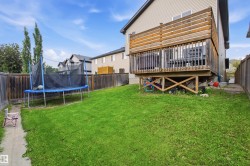 Expansive backyard featuring a manicured lawn, a raised wooden deck with privacy screening, and a full perimeter wooden fence - 