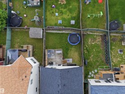 Fenced backyard featuring a wooden deck with outdoor seating, a storage shed, and a trampoline - 