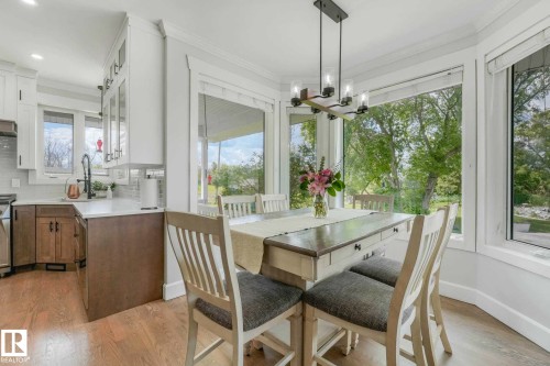 Dining area with a multi-pane bay window, wood-finish flooring, and a modern linear chandelier - 553006 Range Road 153, Rural Two Hills County, AB - Indoor Photo Showing Dining Room