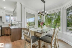Dining area with a multi-pane bay window, wood-finish flooring, and a modern linear chandelier - 