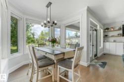 Dining area featuring a bay window, wood-finish flooring, and a contemporary chandelier - 