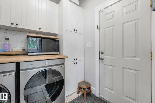 Laundry area featuring white shaker-style cabinetry, wood-finish countertops, stainless steel appliances, and a paneled door - 553006 Range Road 153, Rural Two Hills County, AB - Indoor Photo Showing Laundry Room