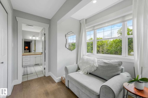 Room featuring large multi-pane windows, wood-finish flooring, and a mirrored wall accent - 553006 Range Road 153, Rural Two Hills County, AB - Indoor Photo Showing Other Room