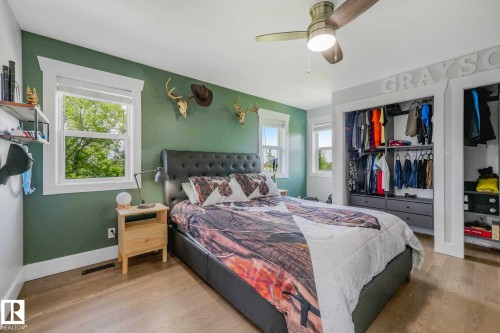 Bedroom featuring wood-finish flooring, a ceiling fan with integrated lighting, and two windows with white trim - 553006 Range Road 153, Rural Two Hills County, AB - Indoor Photo Showing Bedroom