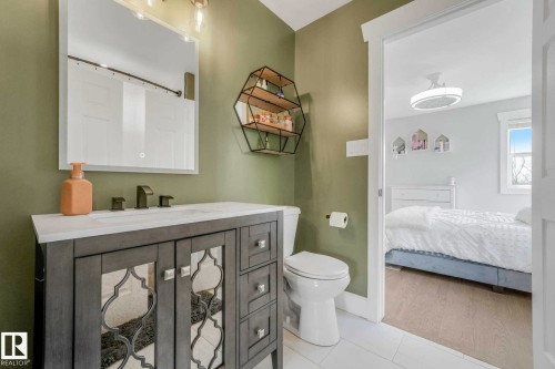 Bathroom featuring a gray vanity with mirrored cabinet doors, a white countertop, and a rectangular mirror with integrated lighting - 553006 Range Road 153, Rural Two Hills County, AB - Indoor Photo Showing Bathroom
