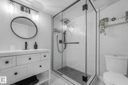 Glass-enclosed shower with black trim and herringbone tile surround - 