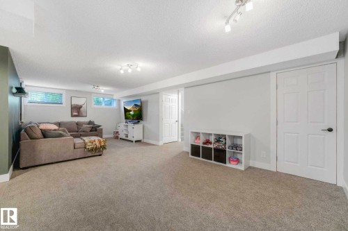 Spacious carpeted room featuring white trim, light gray walls, and track lighting fixtures - 553006 Range Road 153, Rural Two Hills County, AB - Indoor