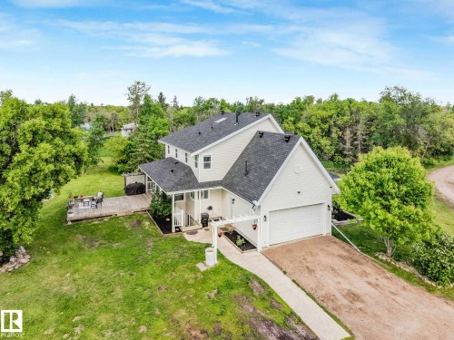 Two-story residence featuring light-colored siding, a dark shingle roof, and an attached garage with a white door - 553006 Range Road 153, Rural Two Hills County, AB - Outdoor