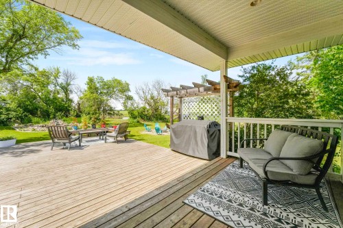 Expansive outdoor deck featuring wood-finish flooring, a covered patio area with a white railing, and a separate open-air patio with a pergola structure - 553006 Range Road 153, Rural Two Hills County, AB - Outdoor With Deck Patio Veranda With Exterior