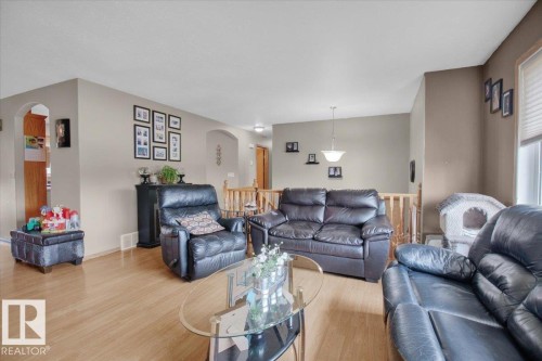 Spacious living area featuring light wood-finish flooring, neutral wall tones, and arched doorways - 5506 53St, Mundare, AB 