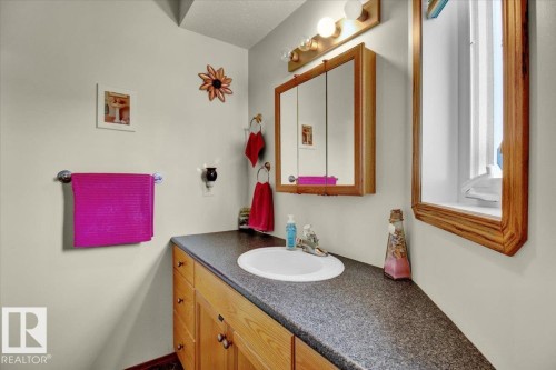 Bathroom featuring a vanity with a white basin sink, dark speckled countertop, and wood-finish cabinetry - 5506 53St, Mundare, AB 