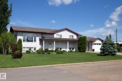 White-sided residence featuring a prominent bay window, attached garage, and mature landscaping - 