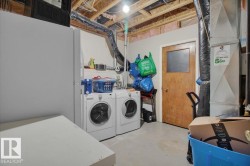 Utility area featuring front-loading washer and dryer, exposed ceiling joists, and a wood-panel door - 