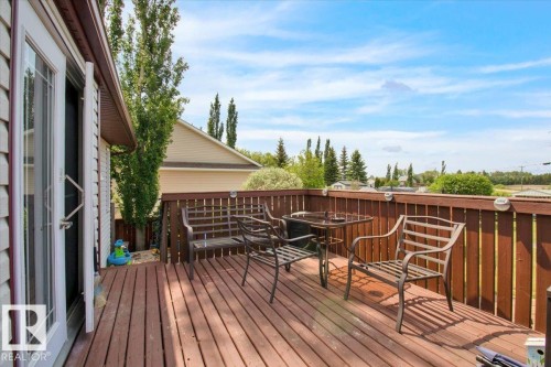 Spacious wood-plank deck featuring a wood railing with integrated lighting and dual glass-paned doors - 5506 53St, Mundare, AB 