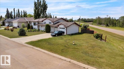 Ranch-style exterior with attached double garage, concrete driveway, and mature landscaping - 5506 53St, Mundare, AB 