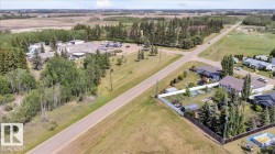Expansive aerial perspective showcasing a rural setting with residential properties, open fields, and forested areas - 