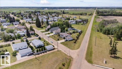 Residential area featuring single-story homes with surrounding green spaces and mature trees - 5506 53St, Mundare, AB 