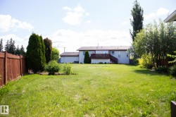 Expansive grassy yard with a wooden privacy fence and mature trees - 