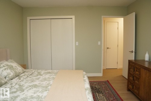 Bedroom featuring light green wall paint, wood-finish flooring, white baseboards, and a bi-fold closet - 25 8930 99 Avenue, Fort Saskatchewan, AB 
