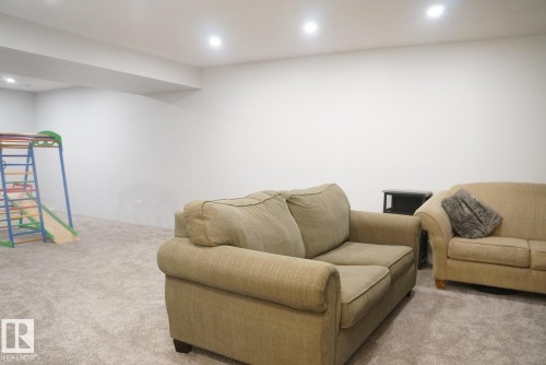 Spacious recreation room featuring recessed lighting, a neutral carpet, and a white ceiling with exposed beam - 25 8930 99 Avenue, Fort Saskatchewan, AB 