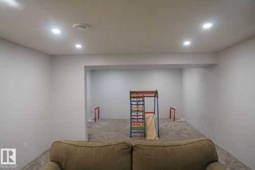 Expansive room featuring recessed lighting, plush carpeting, and a distinct architectural alcove - 25 8930 99 Avenue, Fort Saskatchewan, AB 
