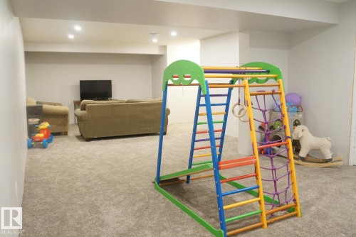 Spacious carpeted room featuring recessed lighting and structural columns - 25 8930 99 Avenue, Fort Saskatchewan, AB 