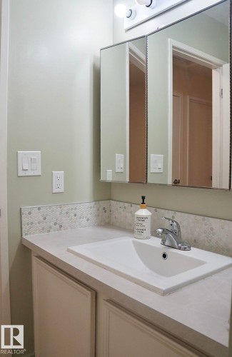 Bathroom vanity featuring a light-toned countertop with an integrated rectangular sink - 25 8930 99 Avenue, Fort Saskatchewan, AB 