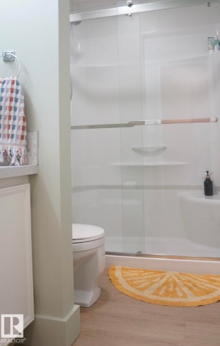 Shower and toilet area featuring a sliding glass shower door - 25 8930 99 Avenue, Fort Saskatchewan, AB 