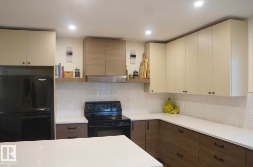 Modern kitchen featuring recessed lighting and a combination of light-toned upper cabinetry with wood-finish lower cabinetry - 25 8930 99 Avenue, Fort Saskatchewan, AB 
