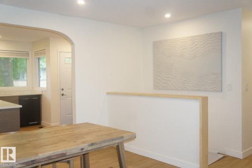 Open-concept living space featuring wood-finish flooring, recessed lighting, a kitchen with a white countertop and dark cabinetry, and an arched doorway - 25 8930 99 Avenue, Fort Saskatchewan, AB 