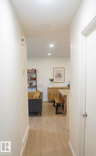 Recessed lighting illuminates the wood-finish flooring throughout this interior space, featuring light-toned walls and crisp white baseboards - 25 8930 99 Avenue, Fort Saskatchewan, AB 