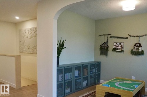 Archway entry to a room featuring light green walls, a semi-flush ceiling light fixture, and wood-finish flooring - 25 8930 99 Avenue, Fort Saskatchewan, AB 