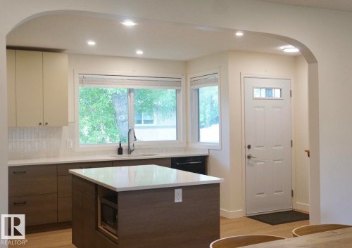 Kitchen featuring two-tone cabinetry, a central island with countertop, and integrated microwave - 25 8930 99 Avenue, Fort Saskatchewan, AB 