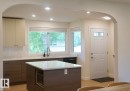 Kitchen featuring two-tone cabinetry, a central island with countertop, and integrated microwave - 25 8930 99 Avenue, Fort Saskatchewan, AB 