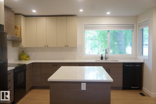 Modern kitchen featuring a central island with a solid surface countertop - 25 8930 99 Avenue, Fort Saskatchewan, AB 