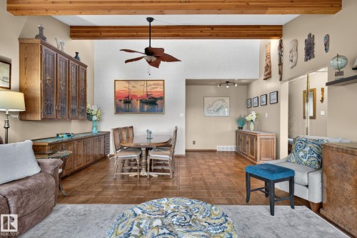 Open-concept living space with exposed wood beams, a ceiling fan, and wood-finish flooring - 5808 Austin O'Brien Road, Edmonton, AB 