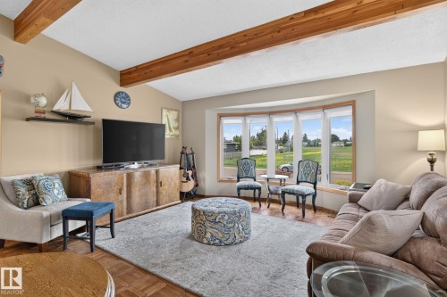 Living area with vaulted ceilings, exposed wood beams, bay windows, parquet wood-finish flooring, and built-in media console - 5808 Austin O'Brien Road, Edmonton, AB 