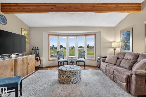 Living area featuring exposed wood ceiling beams and a bay window - 5808 Austin O'Brien Road, Edmonton, AB 
