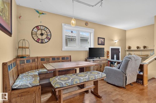 Open-concept room featuring wood-finish flooring, a built-in corner dining bench, a coordinating dining table, and a white-framed window - 5808 Austin O'Brien Road, Edmonton, AB 