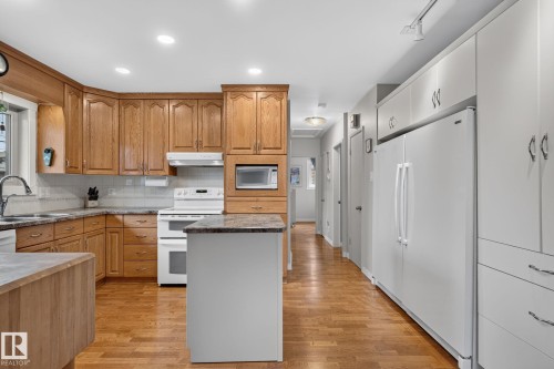 Kitchen featuring a white appliance suite, wood-finish flooring, and recessed lighting - 5808 Austin O'Brien Road, Edmonton, AB 