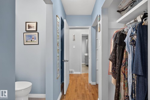 Hallway of ensuite featuring wood-finish flooring, light blue wall paint, white trim, and a white interior door - 5808 Austin O'Brien Road, Edmonton, AB 