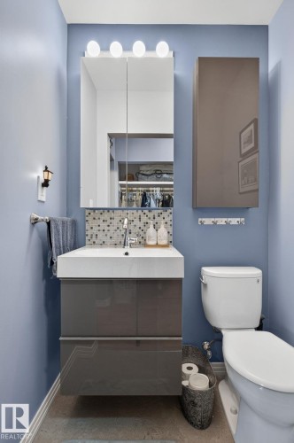 Modern bathroom featuring a floating vanity with integrated sink, mosaic tile backsplash, and wall-mounted medicine cabinet with integrated lighting - 5808 Austin O'Brien Road, Edmonton, AB 