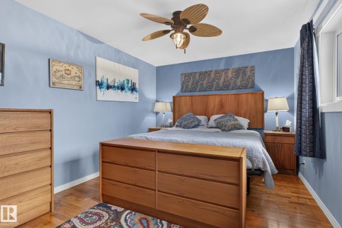 Interior room featuring wood-finish flooring, a ceiling fan with light fixture, and a window with white trim - 5808 Austin O'Brien Road, Edmonton, AB 
