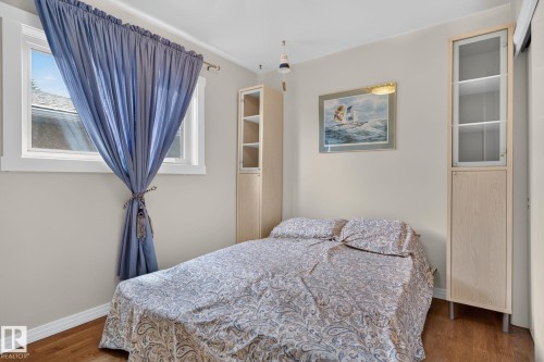 2nd Bedroom Interiors featuring wood-finish flooring, a window with white trim, and light beige wall paint - 5808 Austin O'Brien Road, Edmonton, AB 