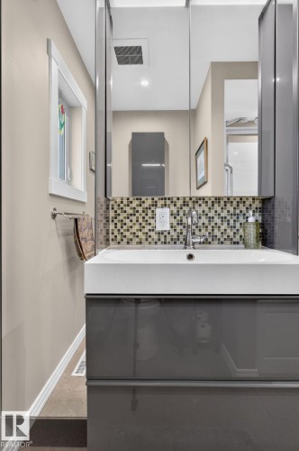 Main BathroomModern bathroom vanity featuring a gloss gray finish, integrated rectangular sink, and a mosaic tile backsplash - 5808 Austin O'Brien Road, Edmonton, AB 