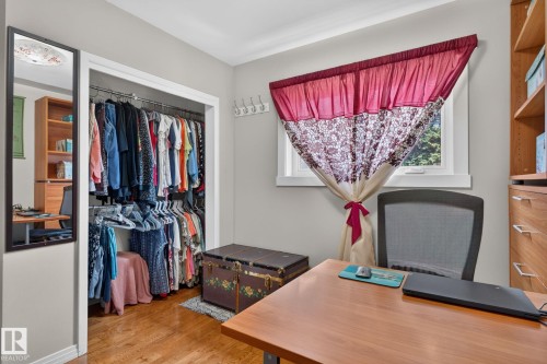 Spacious room featuring hardwood flooring, a built-in closet with ample hanging storage, and a window with white trim - 5808 Austin O'Brien Road, Edmonton, AB 