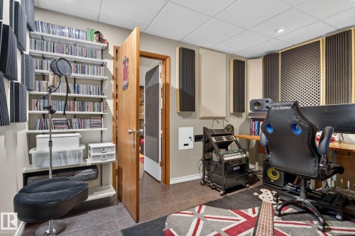 Dedicated sound-treated room featuring acoustical wall panels, built-in shelving, a natural wood-finish door, and a drop ceiling with recessed lighting - 5808 Austin O'Brien Road, Edmonton, AB 