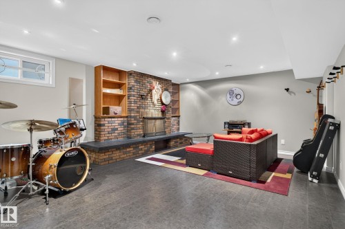 Spacious recreational area featuring a brick fireplace with an extended hearth, built-in wooden shelving, and recessed lighting - 5808 Austin O'Brien Road, Edmonton, AB 