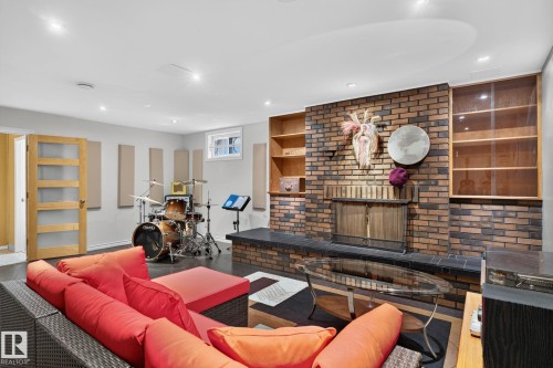 Exposed brick fireplace with a raised hearth and integrated wood shelving, recessed lighting, and a modern glass-paneled door - 5808 Austin O'Brien Road, Edmonton, AB 